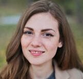 Close-up portrait of a smiling woman with freckles and long hair in a Budapest park during fall.